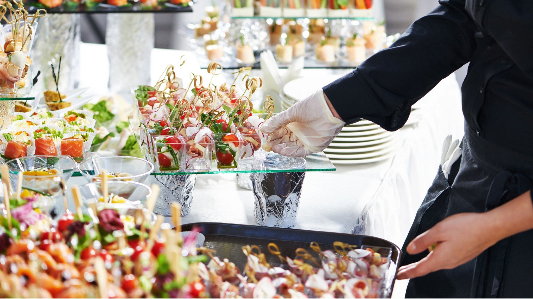Camarero sirviendo bandeja de canapés variados en un evento de catering